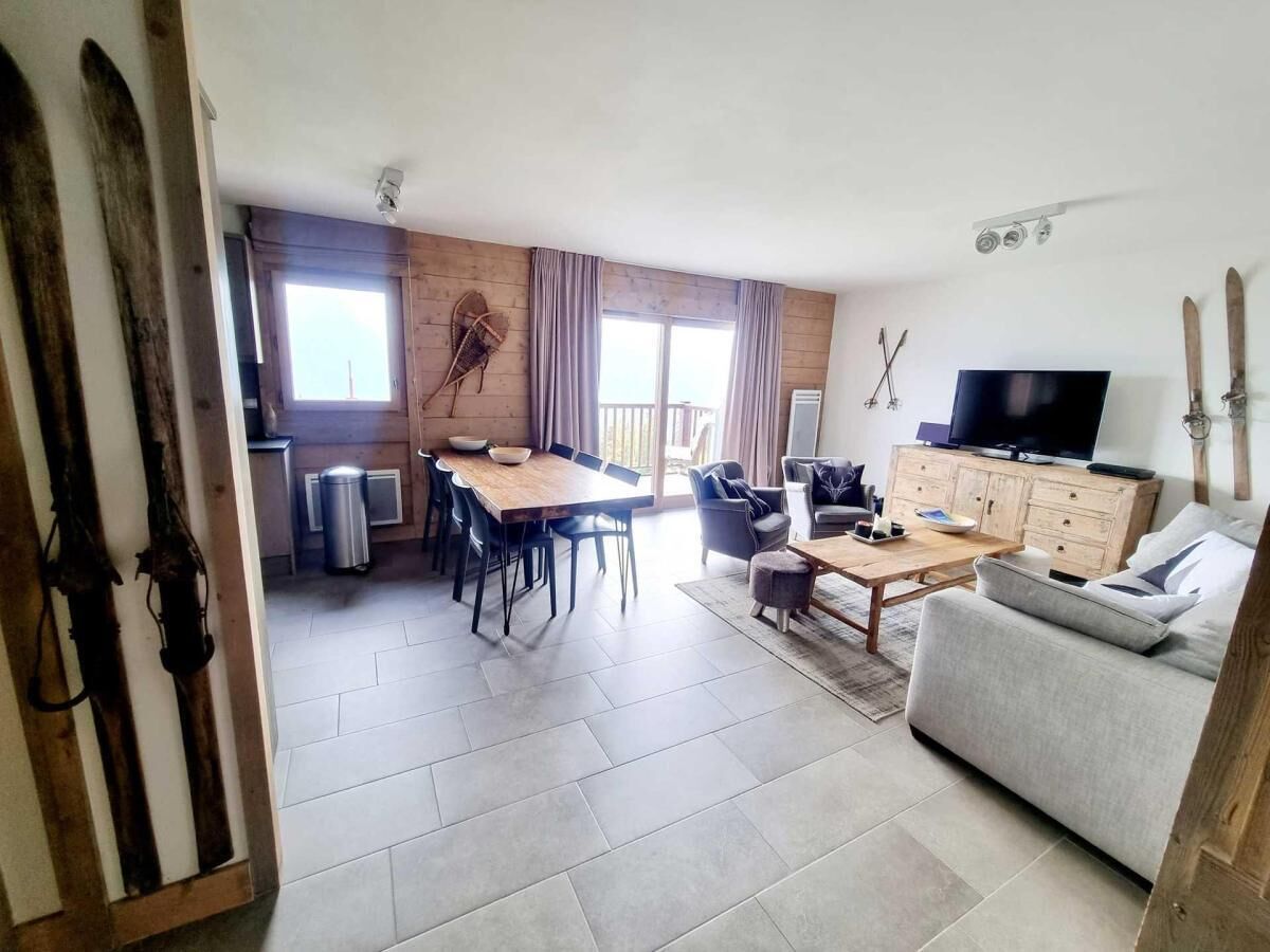 Ein geräumiger Wohnbereich mit Esstisch, Sofa und Fernseher.