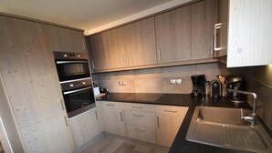 A modern kitchen with wooden cabinets, a stainless steel sink, and a built-in oven. - 100m from ski slopes, 3rd floor, view panoramic, swimming pool, balcony, parking, tv, ski locker (Villard-sur-Doron)
