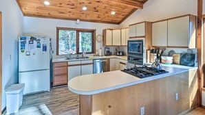 Une cuisine moderne avec des meubles en bois, un îlot central, un four encastré et un réfrigérateur.