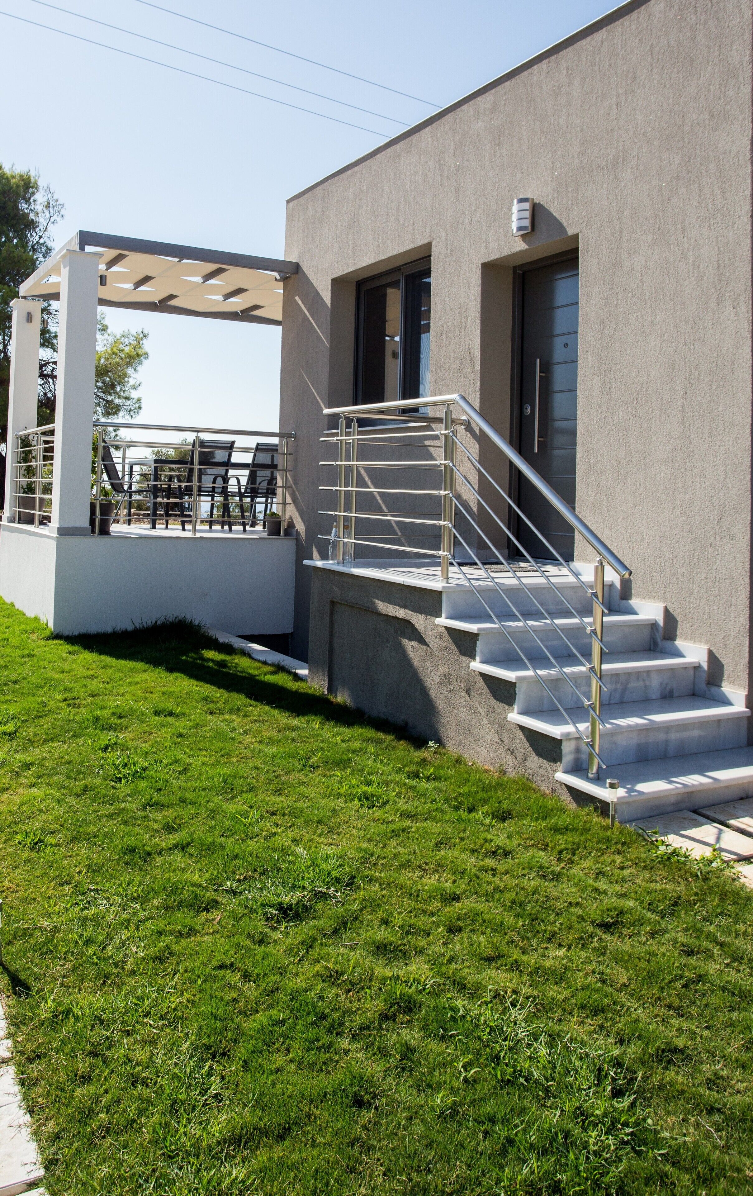 Un edificio moderno con un área de estar al aire libre cubierta y una escalera que conduce a la entrada.