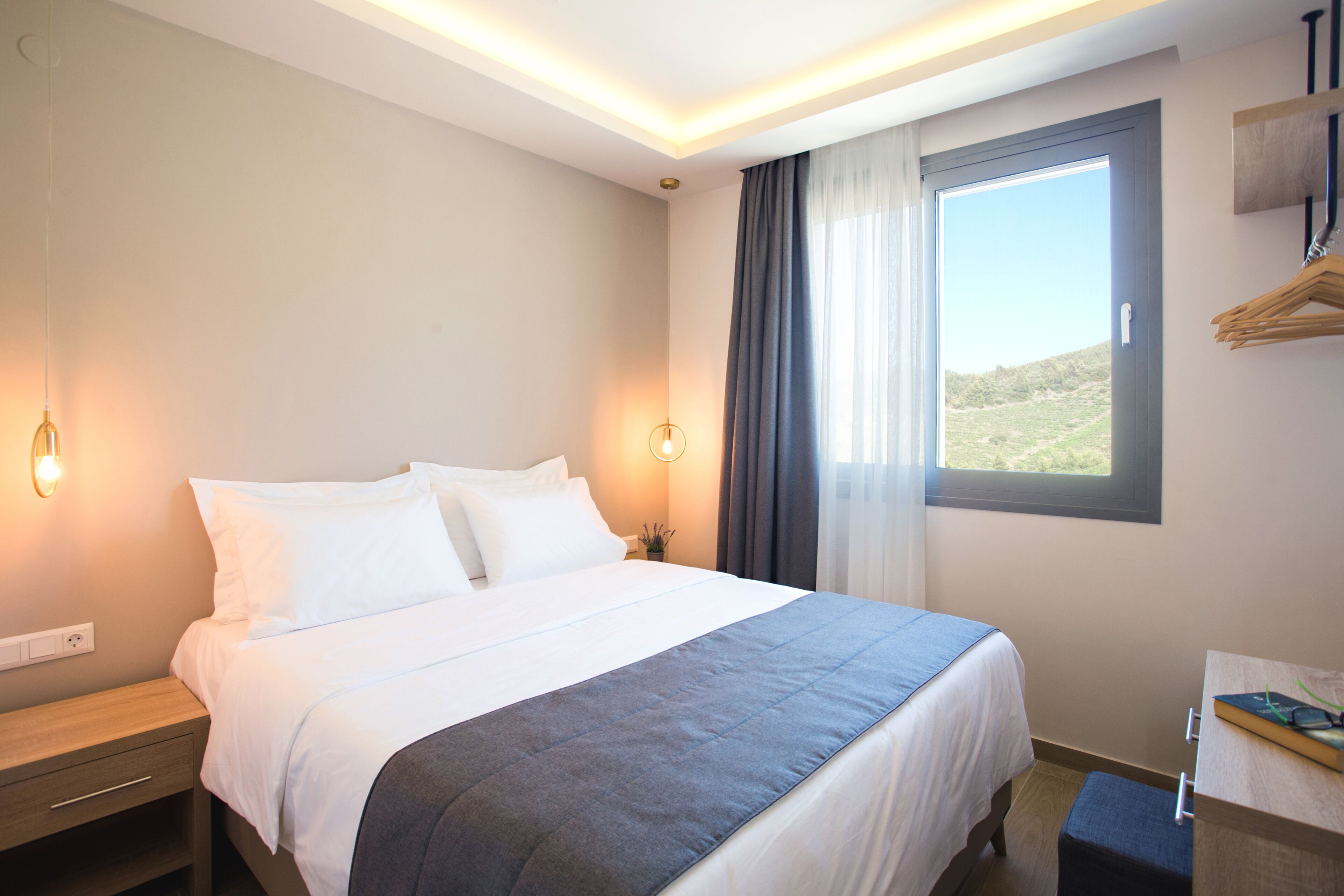 Une chambre d’hôtel avec un lit, une table de chevet et une fenêtre avec des rideaux.