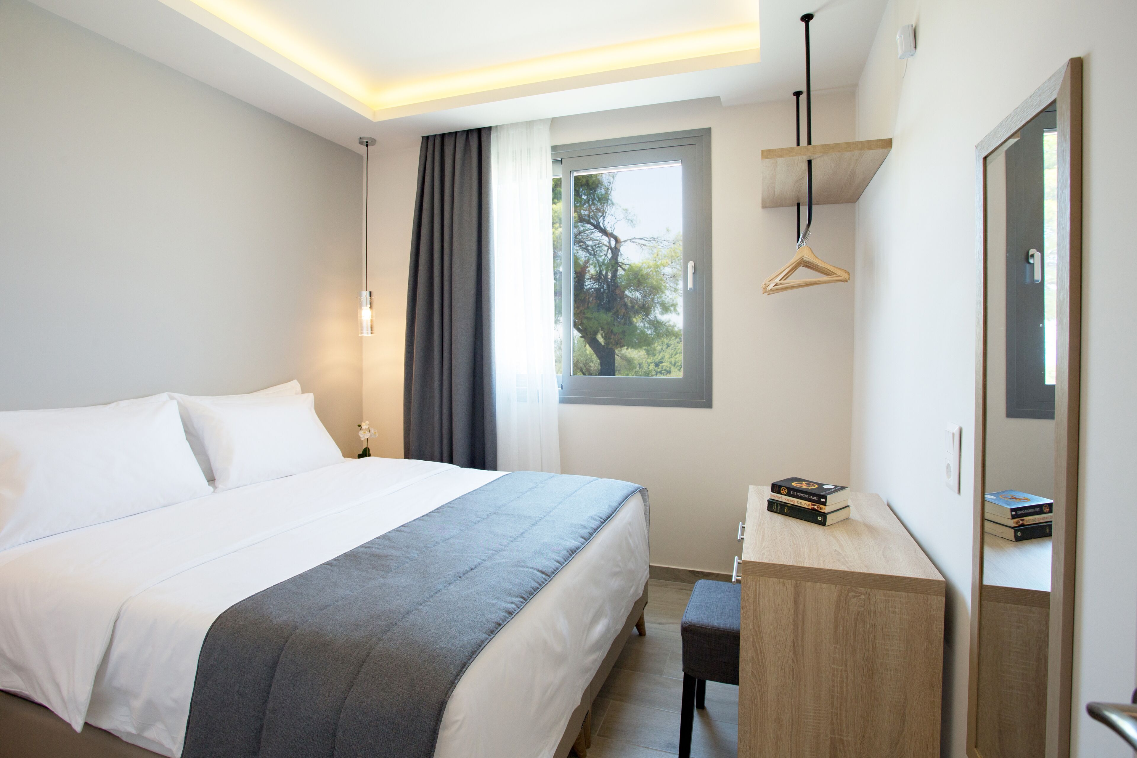 Een moderne hotelkamer met een groot bed, een bureau en een raam met uitzicht op bomen.