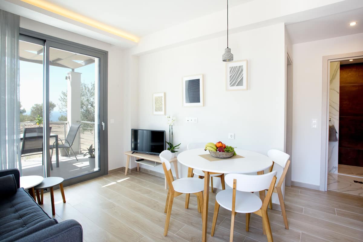 A modern dining area with a round table, white chairs, and a fruit bowl.