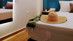 Quarto de hotel com cama, mesa de cabeceira, espelho e luminária na parede.