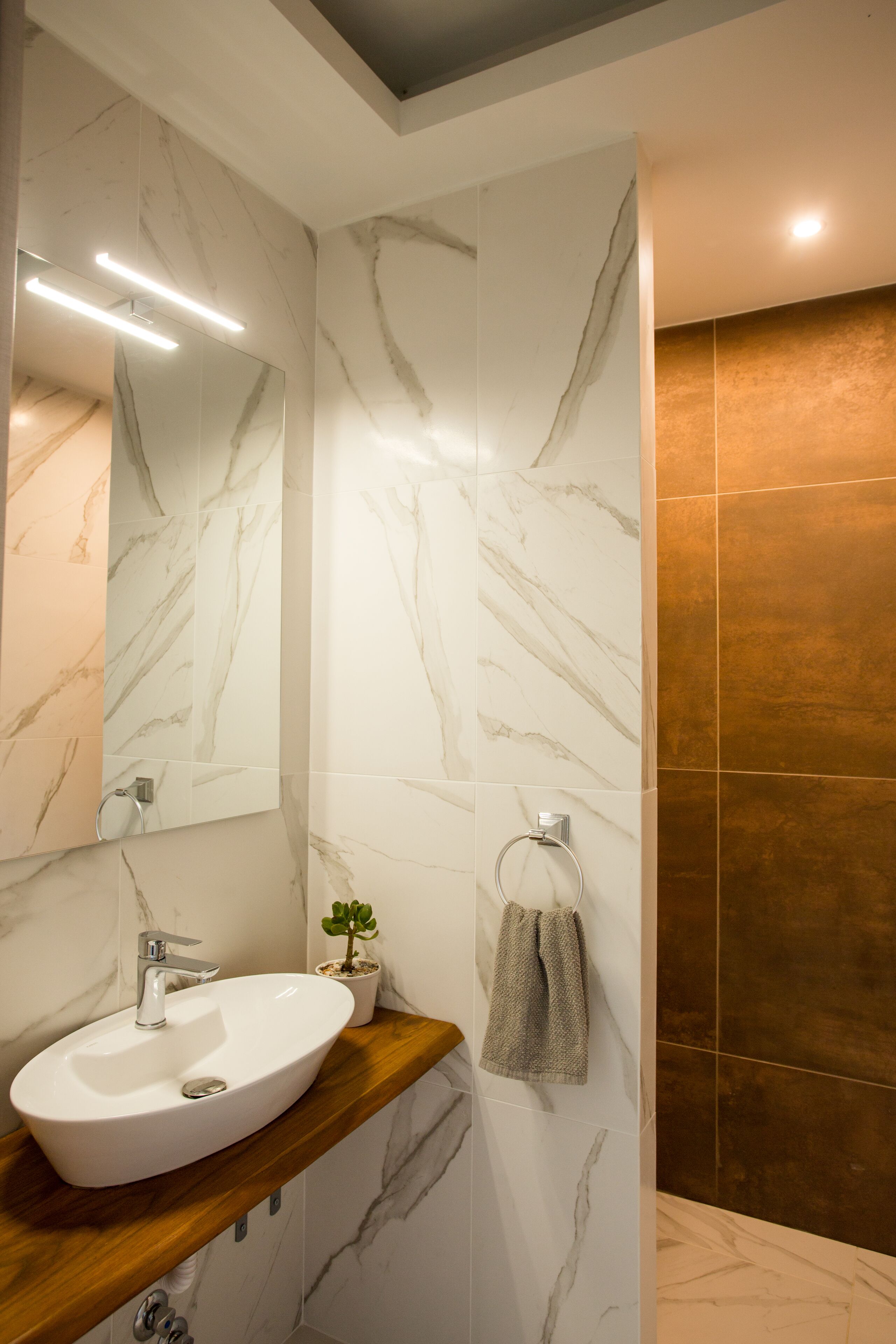 A bathroom with a marble sink, a mirror, and a towel rack.