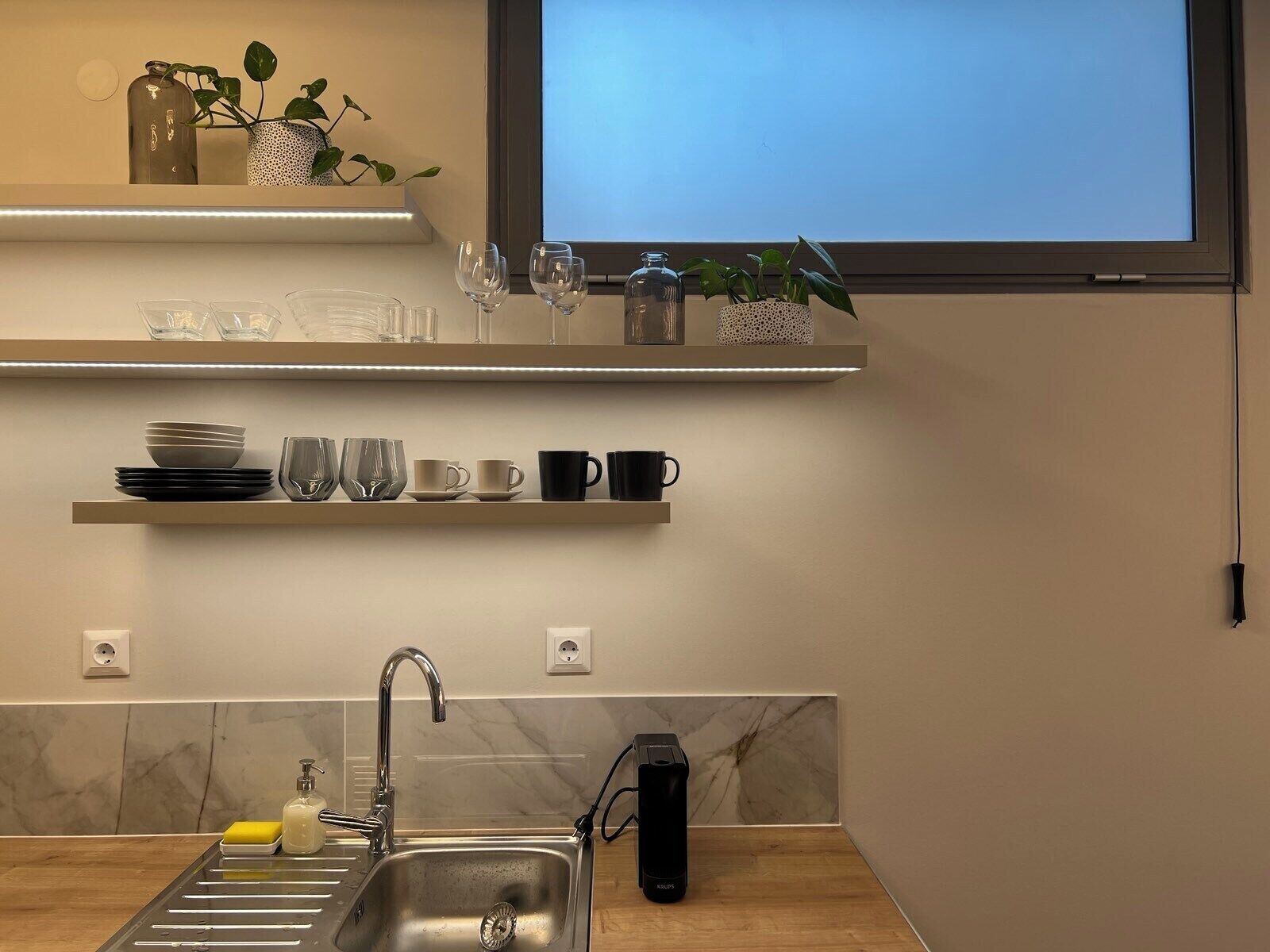 A modern kitchen with a built-in sink, a countertop, and a window above the sink.