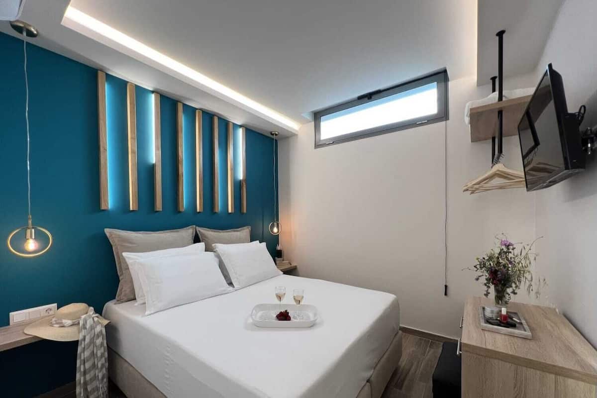 A modern bedroom with a bed, bedside tables, a nightstand, a window, and a mounted TV.