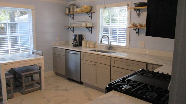 A kitchen with a stove, dishwasher, sink, and a window with blinds. - Beautiful vintage cottage remodeled in Old Ocean Springs (Ocean Springs)