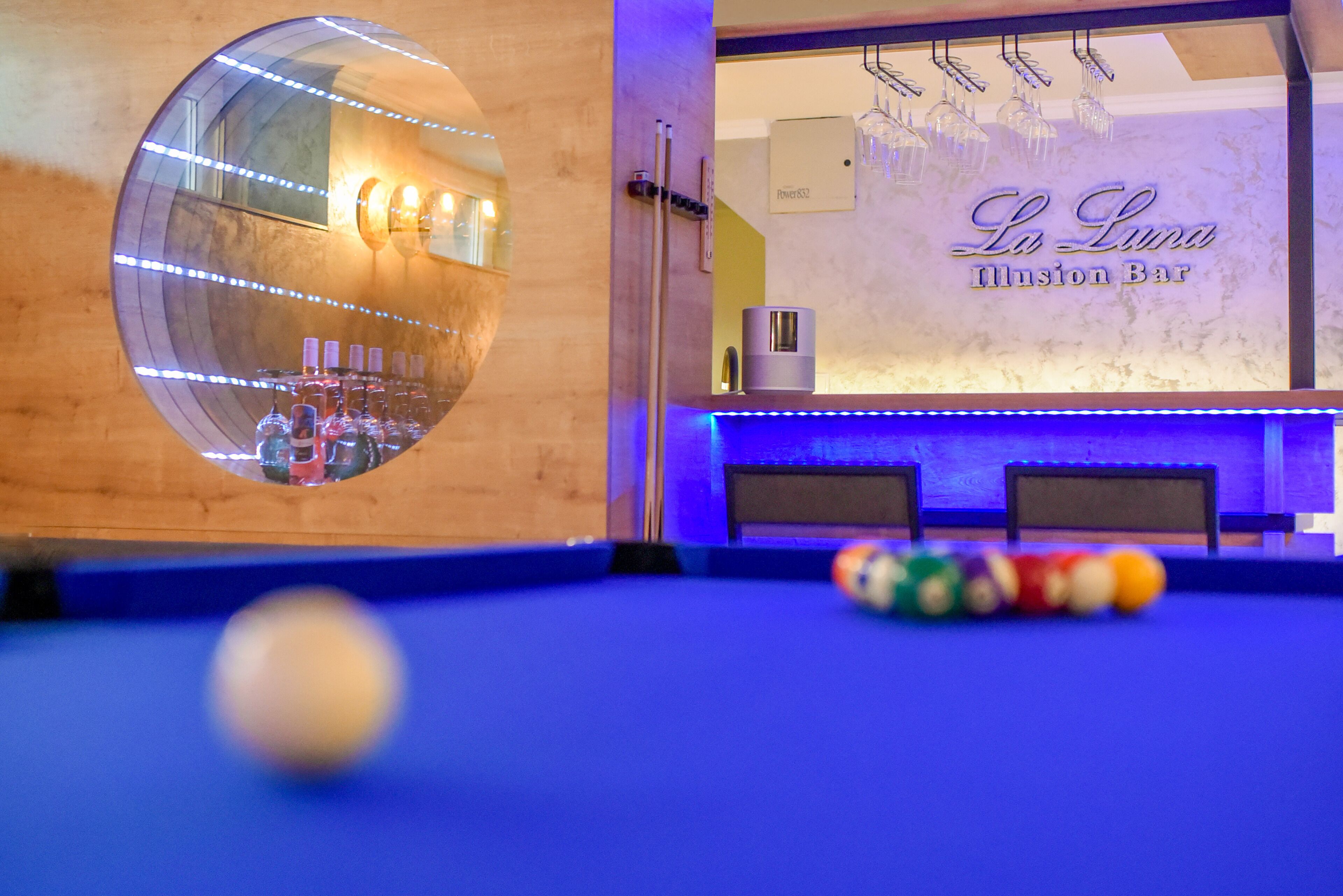 A pool table with balls, a mirror, and a bar area with a sign reading "La Luna Illusion Bar".
