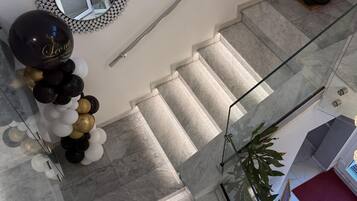 Una scala con gradini in marmo, ringhiera in vetro e un'elegante composizione floreale a forma di palloncino.