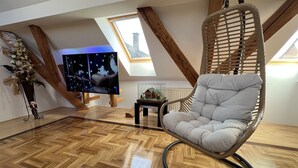 A modern loft bedroom with a wooden floor, a hanging chair, a television, and a small table with a model house. - La Luna ⭐⭐⭐⭐⭐ Rustic Deluxe Apartment with Pool & Jacuzzi Bikes and Parking (Našice)