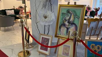 Una galería con obras de arte enmarcadas expuestas, una barrera de cuerda roja y un sofá verde al fondo.