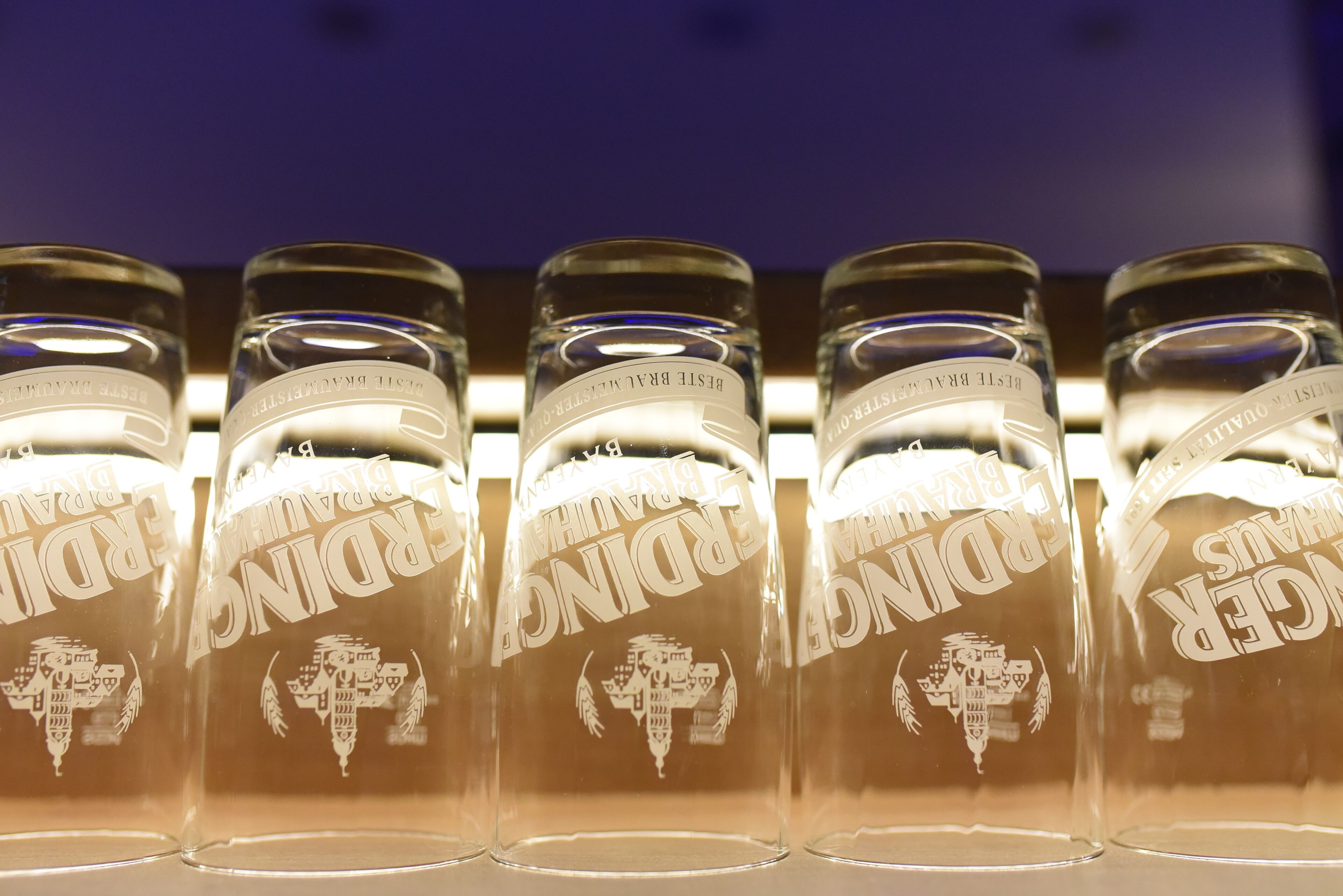 A row of clear glass bottles with embossed text and a logo, likely containing a beverage.