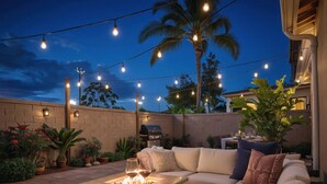 Une terrasse extérieure avec un canapé, une table avec des verres et un barbecue.
