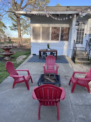 Une terrasse avec des fauteuils Adirondack rouges, une petite table et un foyer.