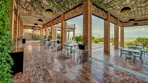 An outdoor patio with brick columns, tables, and chairs, featuring a view of the landscape. - Ampelo Resort (Gurjaani)