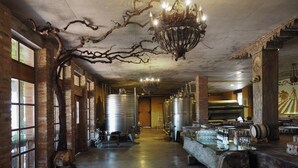 A wine cellar with exposed brick walls, large metal tanks, and a bar area with glasses and bottles. - Ampelo Resort (Gurjaani)
