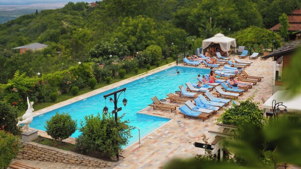 A pool area with lounge chairs and a view of a lush green landscape. - Ampelo Resort (Gurjaani)