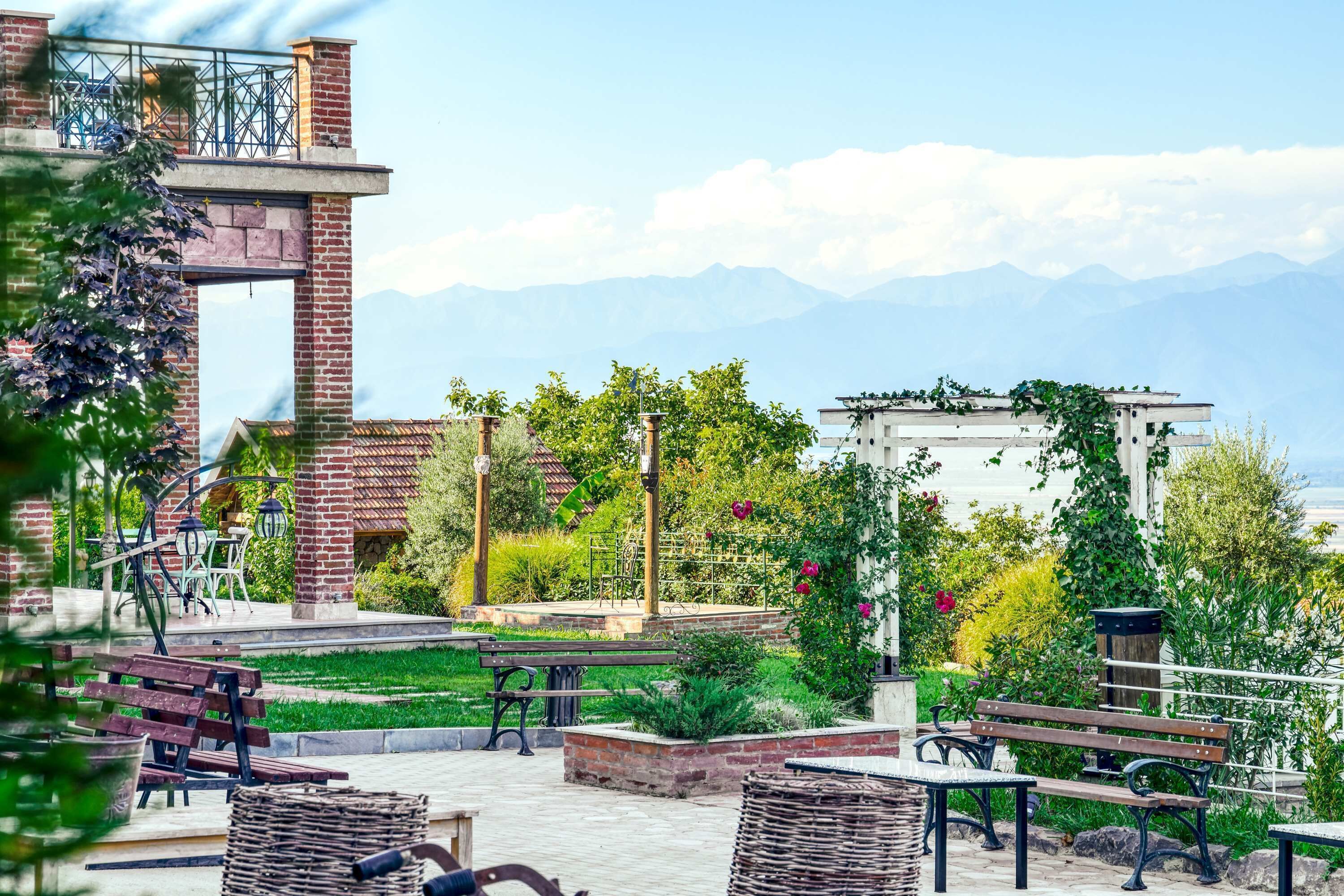 Un patio con mobiliario exterior, una estructura de ladrillo y vistas a montañas.