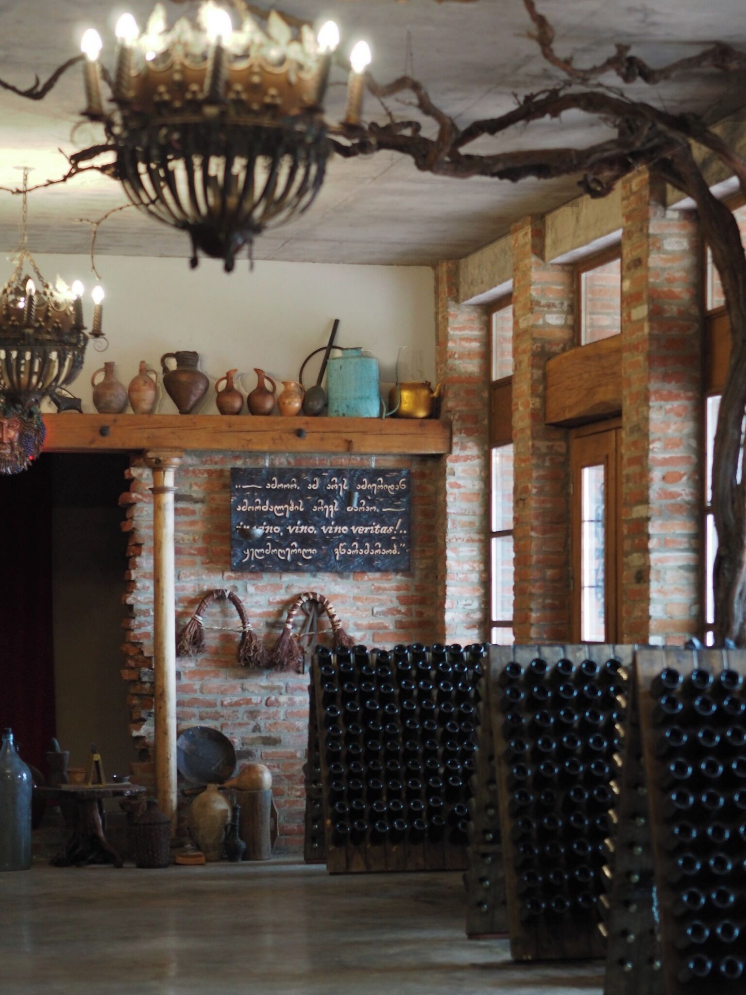 A rustic interior with a brick wall, a chandelier, and a wine rack.