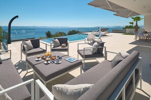 Eine Dachterrasse mit Pool, Liegestühlen und einem mit Frühstück gedeckten Tisch.