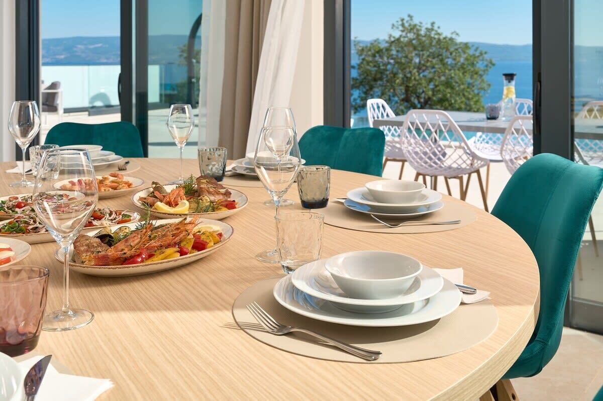 Une table à manger dressée avec des assiettes, des verres et des couverts, offrant une vue panoramique.