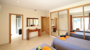 Habitació d'hotel amb un gran mirall, un escriptori de fusta, dos llits amb almoades taronges i vista a l'exterior.