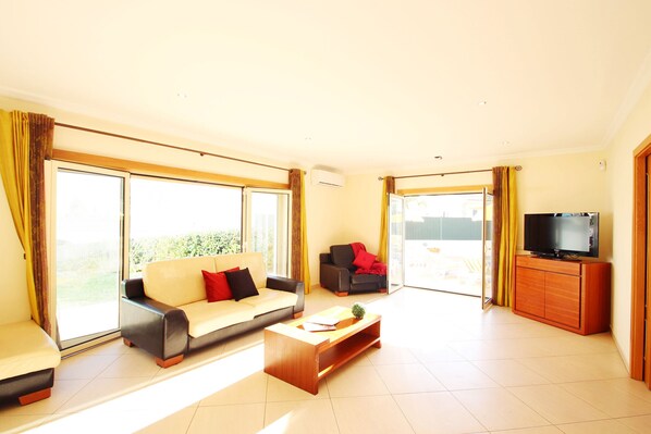 A spacious living room with a sofa, a coffee table, and a television. - Villa w/ heatable pool & BBQ in Albufeira (Albufeira)