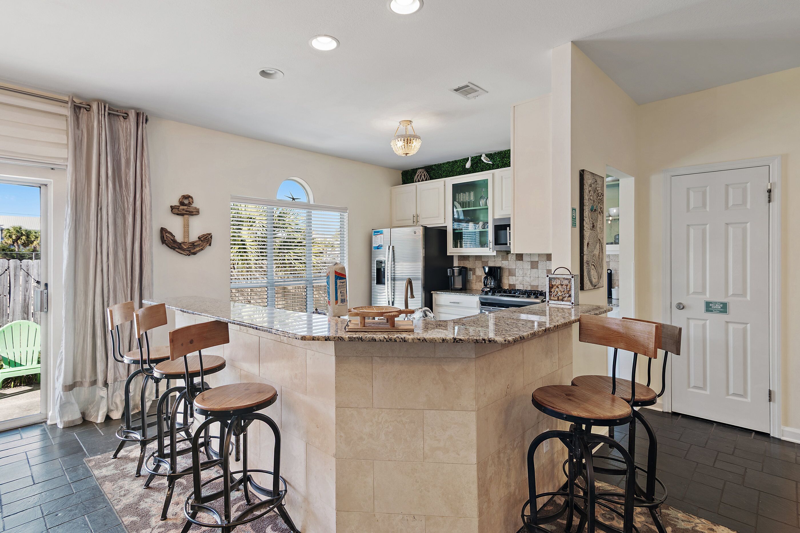 A kitchen with a central island, bar stools, and a view of the outside.