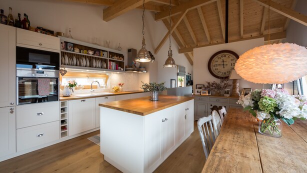 Una cocina amplia con vigas de madera, armarios blancos y una isla central.