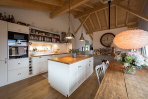 A spacious kitchen with wooden beams, white cabinetry, and a central island.