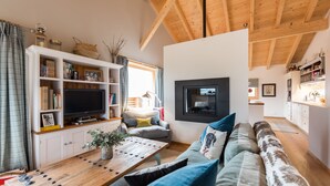 Una sala de estar acogedora con techo de madera, televisor de pantalla plana, sofá y una mesa de centro.