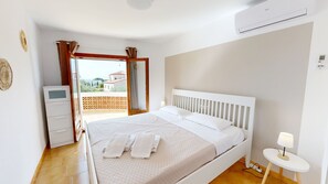 Un dormitorio con cama, mesita de noche, lámpara, equipo de aire acondicionado y vistas al exterior.