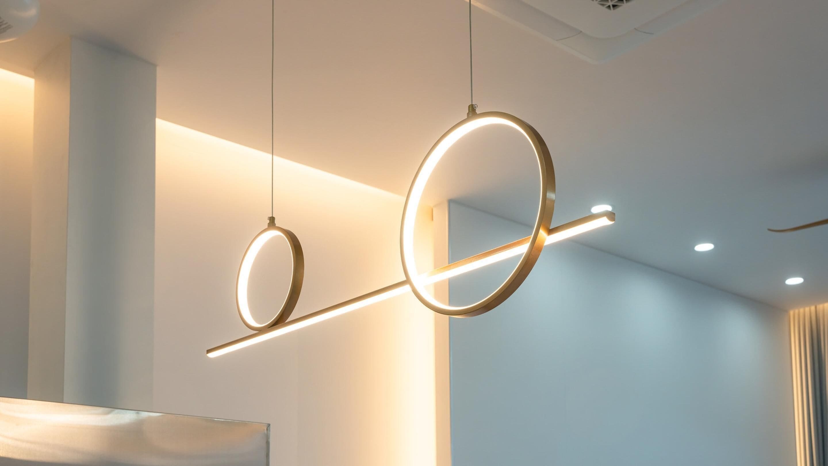 Un intérieur moderne agrémenté de deux luminaires suspendus de forme circulaire et d’une bande lumineuse linéaire.