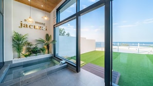 A modern interior with a large glass door leading to a balcony with a view of the sea. - Yeosu Seuteimeong (Yeosu)