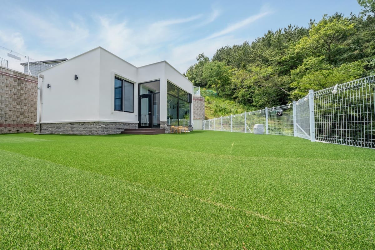 A modern building with a flat roof, large windows, and a well-maintained lawn.