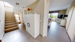 A modern apartment with a staircase, a kitchen area, and a living space with a sofa and TV. - VILLA NIRVANA (El Perelló)