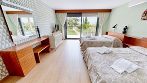 A hotel room with two beds, a desk, a chair, a TV, and a view of the outdoors. - VILLA NIRVANA (El Perelló)