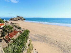 A beach with a rocky outcrop, a clear blue sky, and a sandy shore. - Lunaroxx, 6 Meadow Gardens, Kilgetty (Kilgetty)