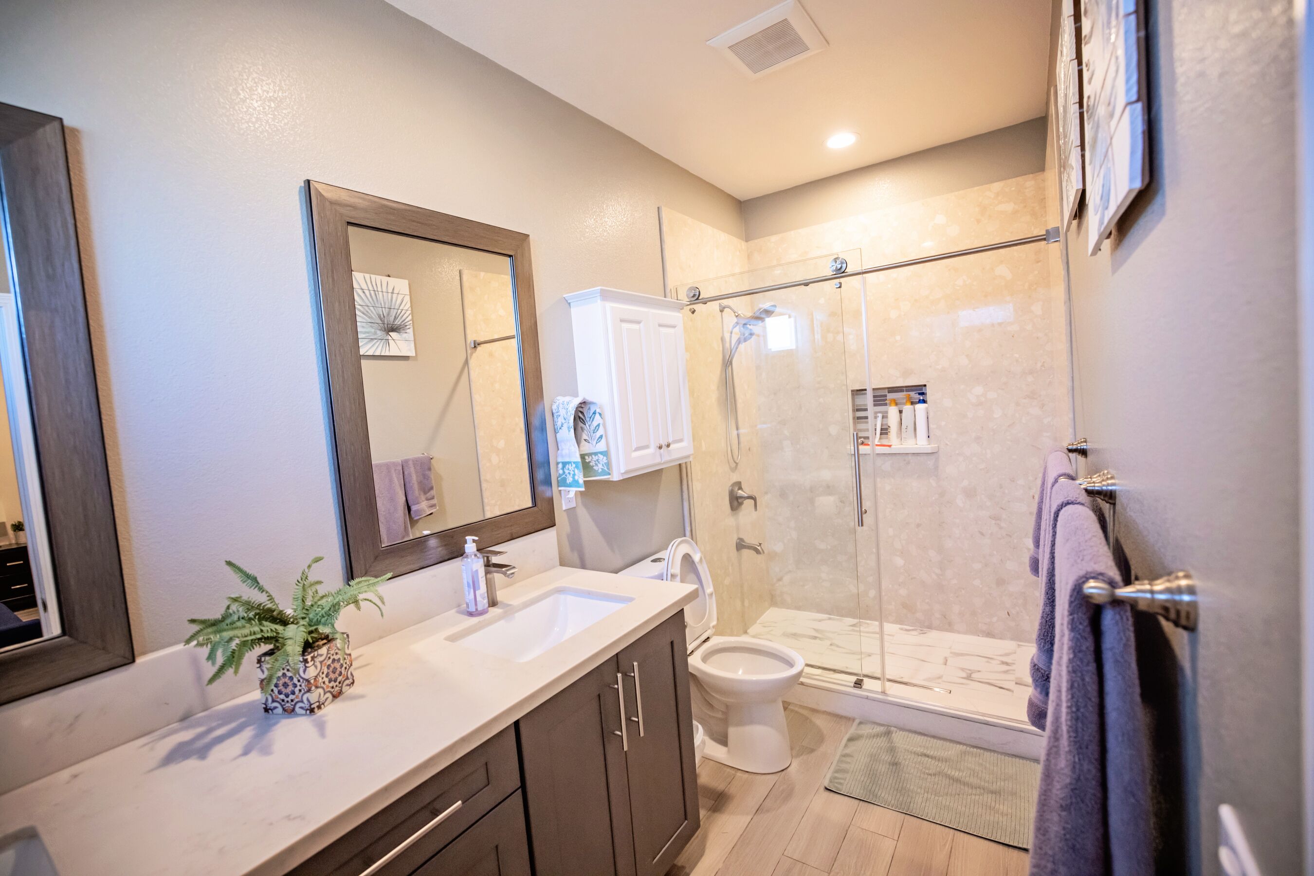 A bathroom with a glass shower enclosure, a sink, and a toilet.
