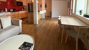 A modern living room with a sofa, coffee table, and dining area with chairs and a table. - Spacious private king suite steps to DT Banff (Banff)
