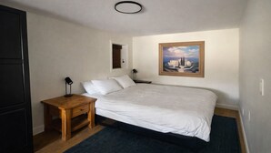 A bedroom with a bed, a nightstand, a painting, and a window with blinds. - Spacious private king suite steps to DT Banff (Banff)