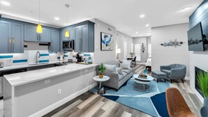 Une cuisine moderne avec des meubles gris, un plan de travail blanc et des luminaires suspendus.