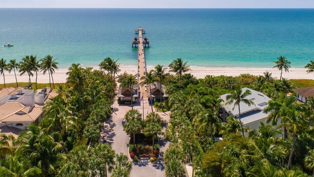 A resort with a beach view, a pier, and palm trees. - Briarwood Vacation Home: Electric Heated Pool with Lake View - Naples, Fl  (Naples)