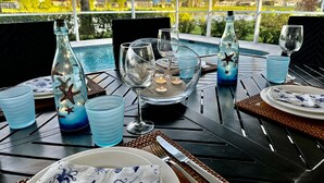 An outdoor dining area with a view of a swimming pool and greenery. - Briarwood Vacation Home: Electric Heated Pool with Lake View - Naples, Fl  (Naples)