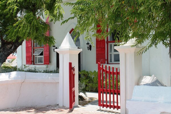 Un bâtiment blanc avec des volets rouges et un portail blanc.