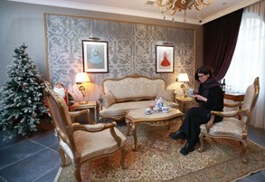 Een traditionele woonkamer met een bank, fauteuils, een salontafel en een kerstboom.