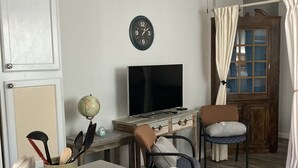 Huoneessa on puinen työpöytä, tuoli, televisio, maapallo ja kattotuuletin.