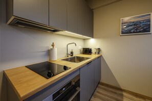 A modern kitchen with a wooden countertop, stainless steel sink, and built-in appliances.
