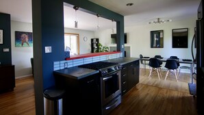Une cuisine moderne dotée d’un îlot central, d’un four encastré et d’un coin repas avec une table et des chaises.